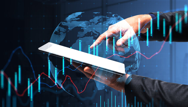 Digital tablet in hands with global financial charts and glowing market indicators overlay illustrating modern data analysis and trading concept.