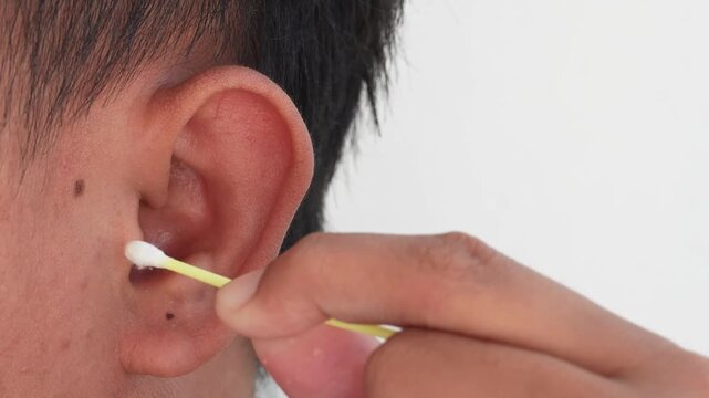 A hand is cleaning the ear with a cotton bud.