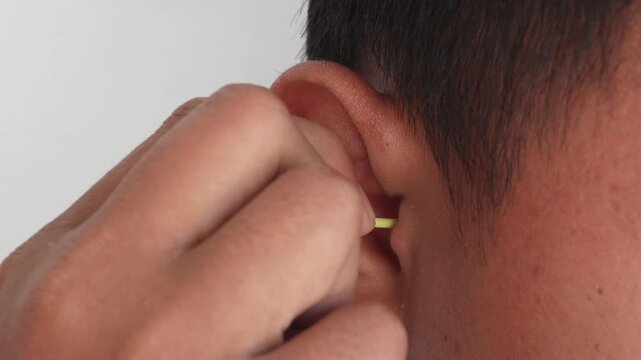 A hand is cleaning the ear with a cotton bud.