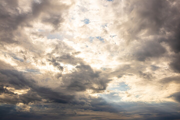 Fototapeta premium Dark Storm Clouds with Sunlight Breaking Through Dramatic Sky. Dramatic storm clouds with rays of sunlight breaking through the overcast sky, creating a powerful weather scene. 