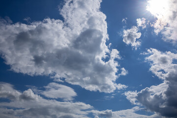 Fototapeta premium Towering White Cumulus Clouds in a Bright Blue Sky. Large white cumulus clouds rising into a clear blue sky on a sunny day. Scenic cloudscape perfect for weather, summer, nature