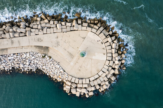 Aerial view of the breakwater and lighthouse featuring concrete tetrapods and stone pier surrounded by the sea in Trani, Apulia, Italy.
