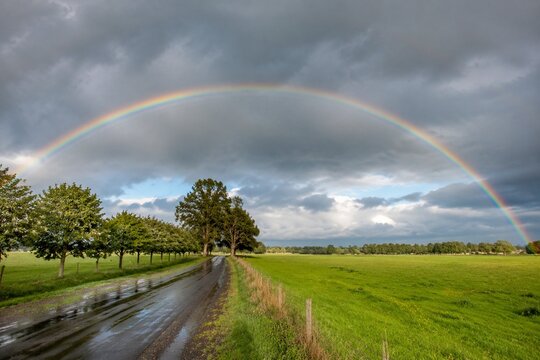 Rainbow across gray storm sky after rain, colors brightening.