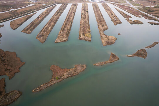 Aerial view of fish farm ponds with parallel water channels and marshy islands in Keramoti, Greece.