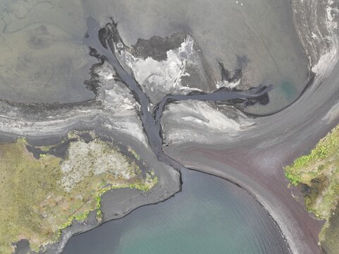 Aerial view of the volcanic landscape of Veidivotn with dark sand deposits, winding river channels, and patches of green moss Hella, Rangarthing ytra, Iceland.