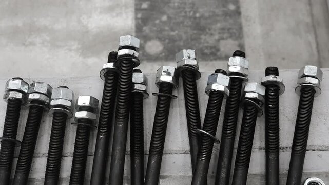 Industrial anchor bolts with hex nuts and washers prepared for steel construction, machinery installation and structural assembly. Engineering, manufacturing and fastening concept.