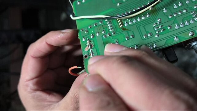 Detailed view of hardware repair process, troubleshooting a circuit board on a workbench