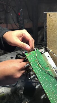 Close up of hands installing wiring and electronics on a PCB at a workshop