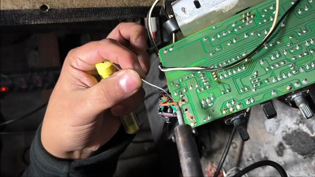 Detailed view of electronics repair process with solder smoke during circuit board assembly