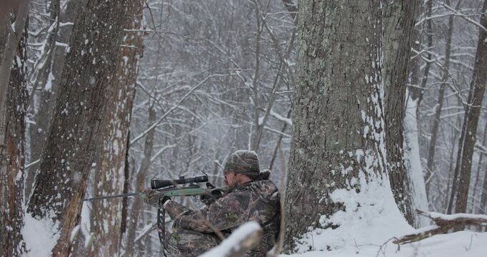 Hunter in Camouflage Firing Rifle During Heavy Snowfall on McClain Mountain, Virginia