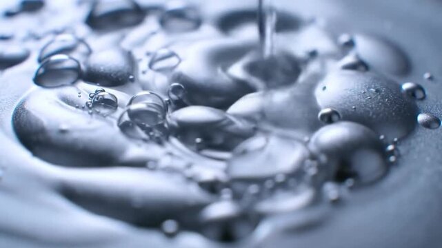 Close-up of mercury liquid metal droplets forming on a surface with small bubbles