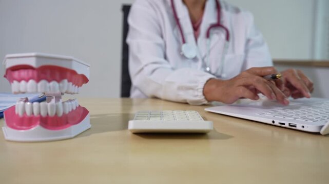 Dentist using calculator to estimate medical bills, insurance coverage, and medication costs in a clinic. Concept of healthcare finance, budgeting, and affordable dental care.