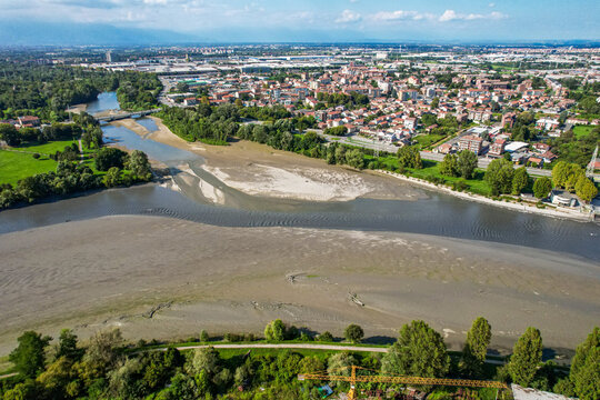 Aerial view of the confluence of the Stura and Po rivers showing exposed riverbeds due to drought, surrounded by urban landscape and green trees. Torino, Piemonte, Italy.