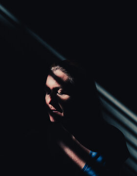 Close up of woman with eyes closed in a sliver of light