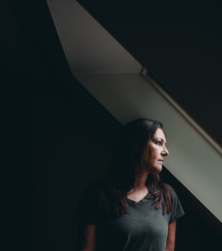 Pensive woman in shadow looks toward window light