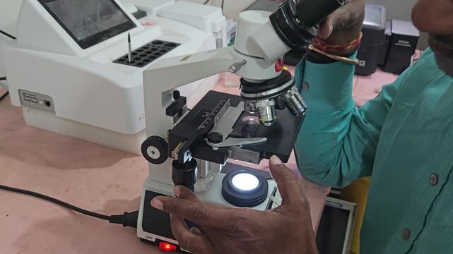 Scientist examining laboratory sample using optical microscope in modern research laboratory. Researcher focusing on microscopic analysis, scientific observation, laboratory diagnostics