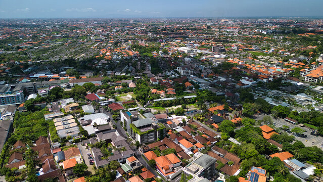 Denpasar, Indonesia - 28 April 2024: Aerial view of the dense urban landscape, featuring a mix of traditional Balinese architecture, modern buildings, and lush green trees.