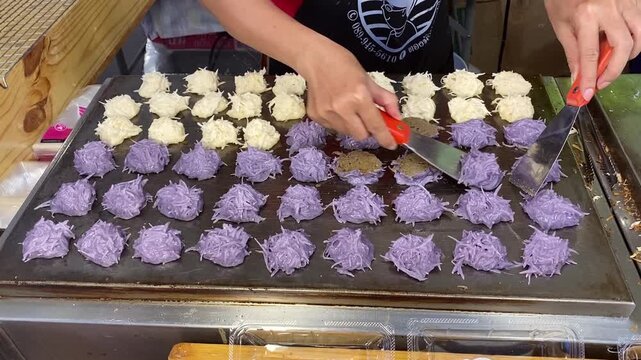 Authentic, Famous Khanom Babin, a Thai Traditional Coconut Milk Pancake Macaroon Dessert. Woman Cooks Fresh on a Hot Skillet at a Asian Bangkok Thailand Open Street Food Market