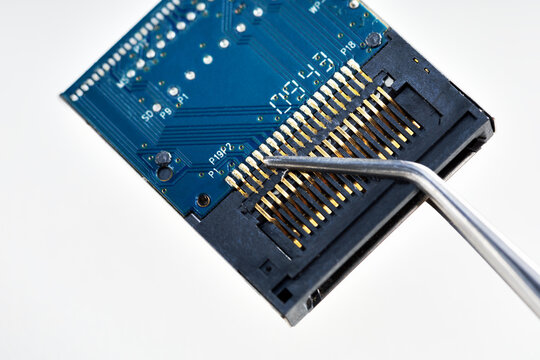 microchip in tweezers, close-up. repair, sale, research and development of microelectronics.