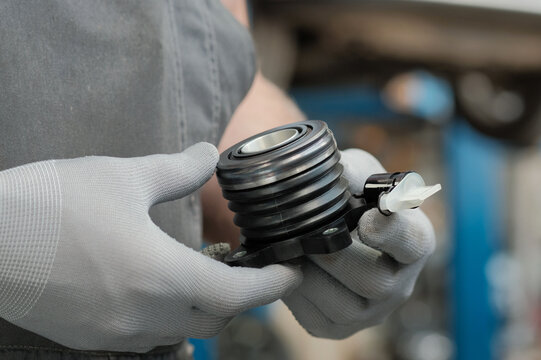 Car service.Gearbox repair.The mechanic holds a release bearing with a clutch.Inspection and control of the serviceability of a new spare part.Replacement of the release cylinder.