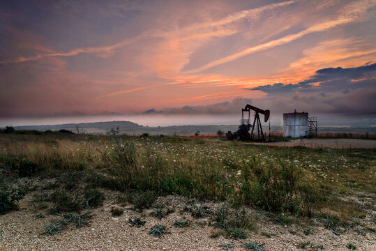 An old oil pumpjack silhouette at sunset in Ayoluengo fields Burgos Spain representing industrial heritage energy production and fossil fuel decline