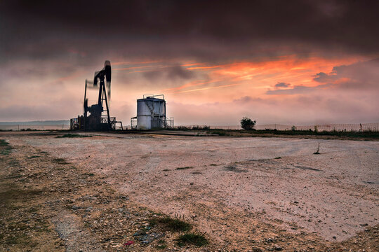 An old oil pumpjack silhouette at sunset in Ayoluengo fields Burgos Spain representing industrial heritage energy production and fossil fuel decline