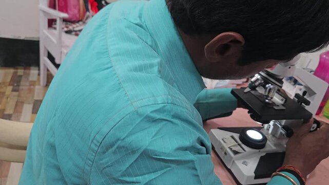 Scientist examining laboratory sample using optical microscope in modern research laboratory. Researcher focusing on microscopic analysis, scientific observation, laboratory diagnostics
