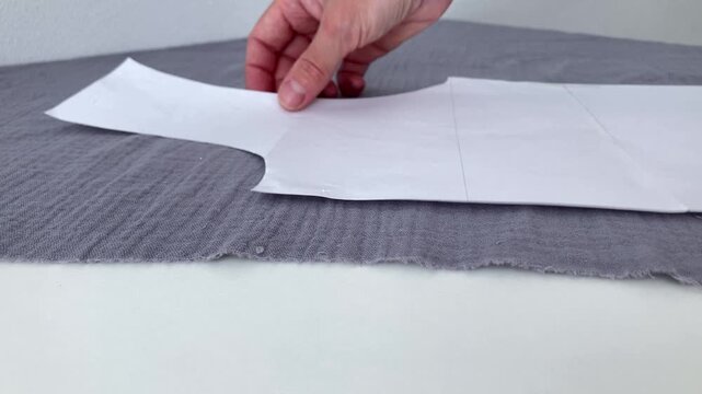 The woman puts the pattern on the fabric. Close-up of a woman's hands with a pattern. Fabric preparation for sewing clothes at home, saving on wardrobe upgrades