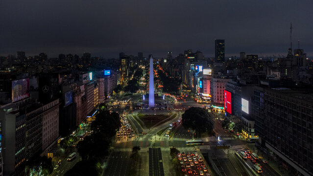 Buenos Aires, Argentina - 07 June 2022: Aerial view of the Obelisco de Buenos Aires illuminated at night, surrounded by busy city streets, glowing traffic lights, and urban architecture.