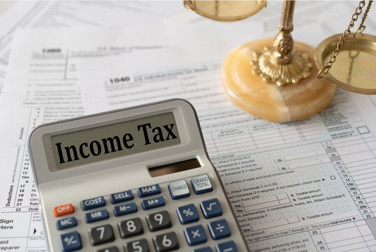 Income tax word in calcualtor screen with individual income tax form and Scales of Justice. taxation law, tax law concept.