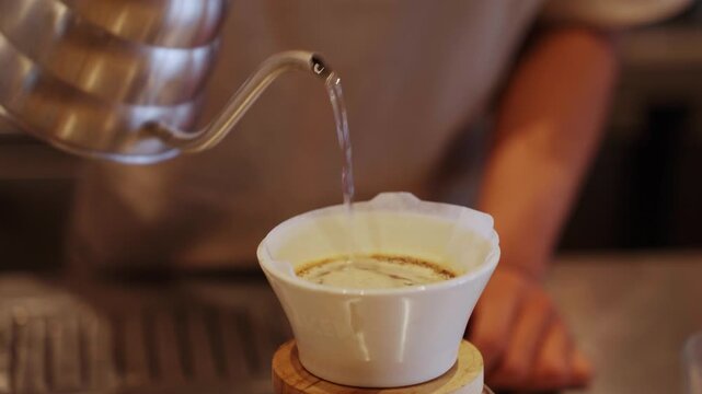 Barista pouring hot water into coffee dripper
