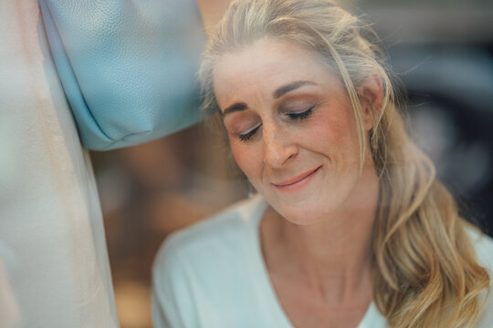 Stylish blonde woman looking through a boutique display window capturing elegance fashion and contemporary shopping culture.