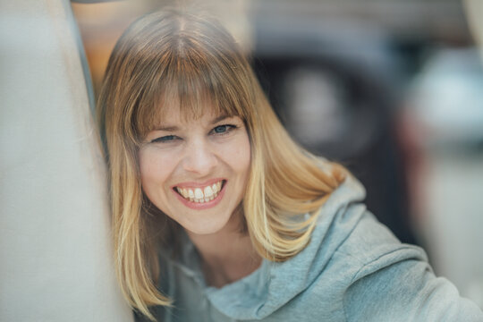Confident blonde woman looking through the fashion store window creating a timeless portrait with elegant urban shopping mood.