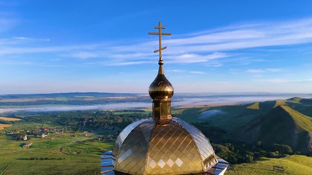 Chapel atop Andreyevskie Shishki Mountain; fog in the valley at dawn; drone panorama in the Orenburg region