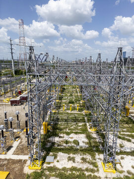 Aerial view of CFE SE Norte electrical substation with complex steel lattice structures, high-voltage equipment, and power lines under a blue sky in Merida, Yucatan, Mexico.