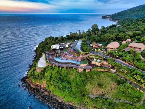 Aerial view of Jemeluk Beach Bungalows featuring a cliffside infinity pool, lush tropical vegetation, and coastal scenery in Kecamatan Abang, Bali, Indonesia.