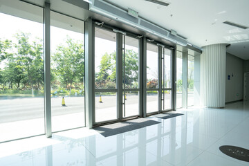 Fototapeta premium Modern office building entrance hall with glass automatic doors and reflective tiled floor