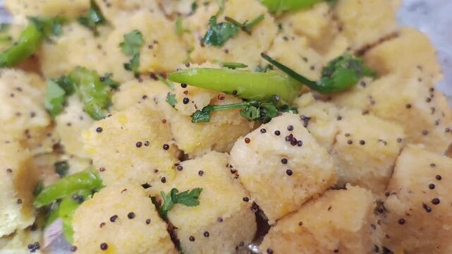 Extreme Close-up of Gujarati Khaman Dhokla Garnish with Green Chili and Mustard Seeds