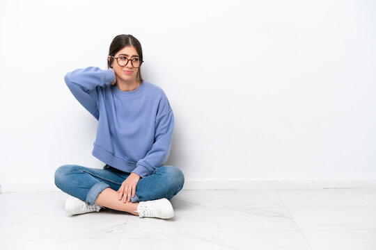 Young caucasian woman sitting on the floor isolated on white background with neckache