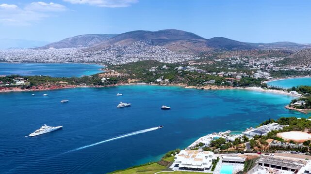 Aerial view of the popular Astir Bay and Beach in Vouliagmeni, south Athens coast, Greece, with turquoise sea and moored luxury yachts during summer time