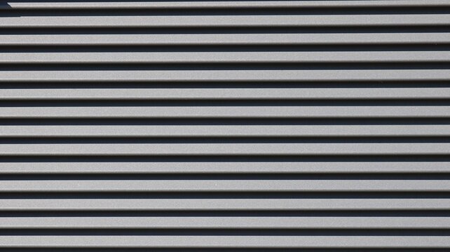 The texture of horizontal metal siding is dark gray. Smooth, parallel panels form a strict geometric pattern, where the alternating protruding edges and deep shadows create volume.