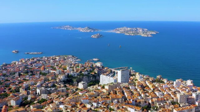 Aerial drone view of Marseille coastline with red rooftops, the Frioul archipelago, Chateau d'If, and the Mediterranean Sea in Marseille, France, daytime.