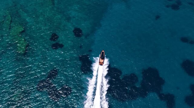 Aerial overhead view of a modern luxury RIB twin outboard motorboat crossing the blue ocean with high speed