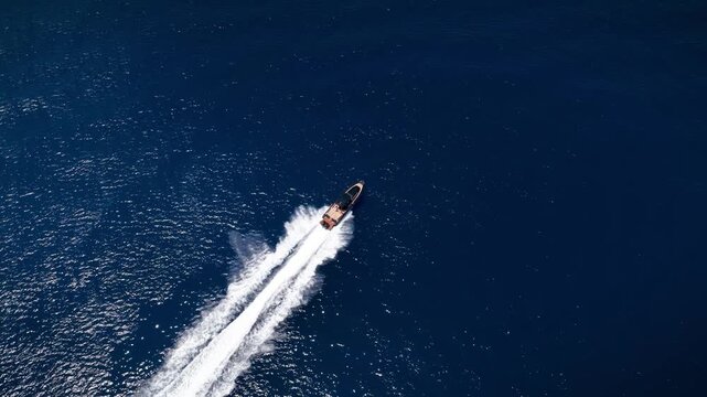 Aerial overhead view of a modern luxury RIB twin outboard motorboat crossing the blue ocean with high speed