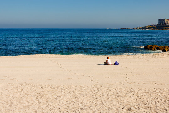 Rear view of a woman relaxing on a sandy beach in La Coru&ntilde;a during a summer vacation.
