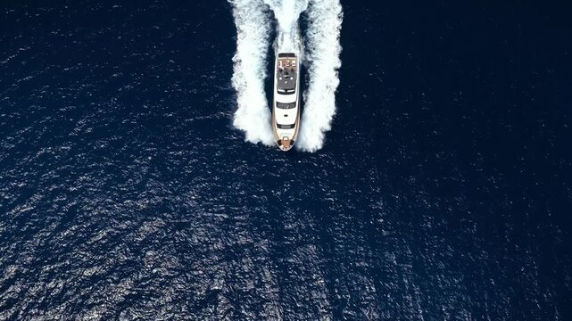 Aerial overhead view of a modern luxury yacht cruising over the blue ocean as a summer travel concept