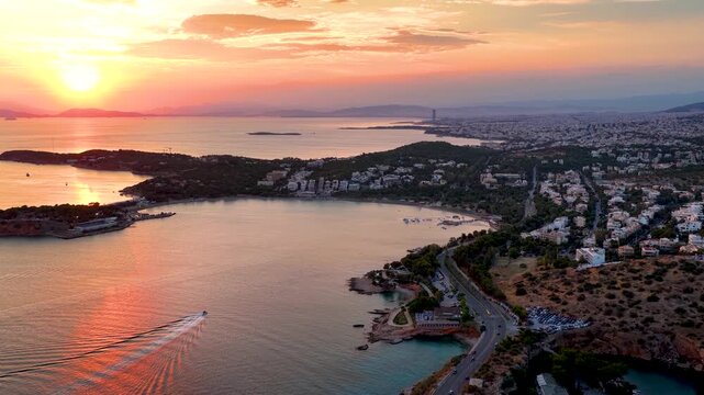 Establishing aerial summer sunset view of the south coast of Athens, Greece, with Vouliagmeni lake, bay and beach, Laimos peninsula and famous Astir beach