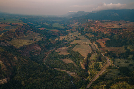 Aerial view of the Puente Beltran bridge winding through the lush green valley and rugged landscape of Tonila, Jalisco, Mexico.