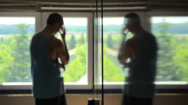 Depressed teenager in a dark room staring at his own reflection. Hiding face in hands and despairing