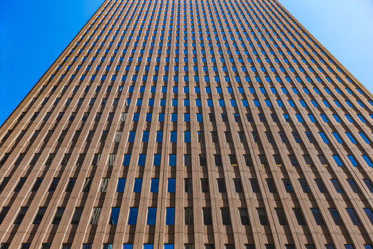 Low angle view of modern office skyscraper with geometric window pattern against blue sky